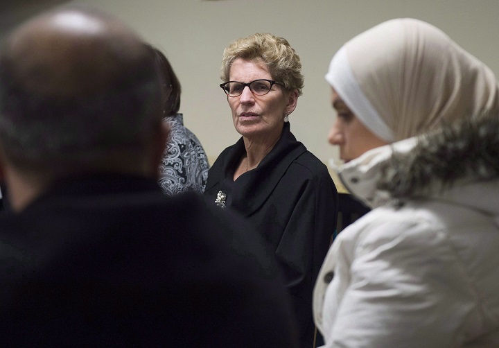 Ontario Premier Kathleen Wynne, centre, speaks with newly-arrived Syrian refugees in Toronto on Friday, December 18, 2015. 