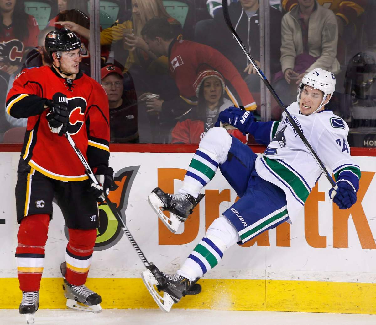 Vancouver Canucks' Adam Cracknell, right, is knocked off his skates by Calgary Flames' Lance Bouma during second period NHL action in Calgary, Alta., Friday Feb. 19, 2016. 