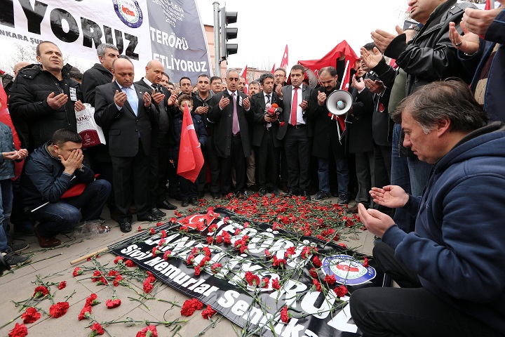 Turkish civil servants pray for the victims as they lay a banner that reads " we condemn terrorism " and carnations at the site of Wednesday's explosion, in Ankara, Turkey, Saturday, Feb. 20, 2016.