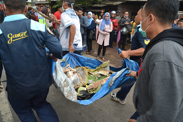 Indonesian officials carry wreckage from a military plane after it crashed while on a test flight from the local air force base into a house in a densely populated area in Malang on February 10, 2016. The Super Tucano turboprop came down shortly after taking off from Abdul Rachman Saleh air force base at Malang in East Java, killing the pilot and two people in the building, an air force official said.      
