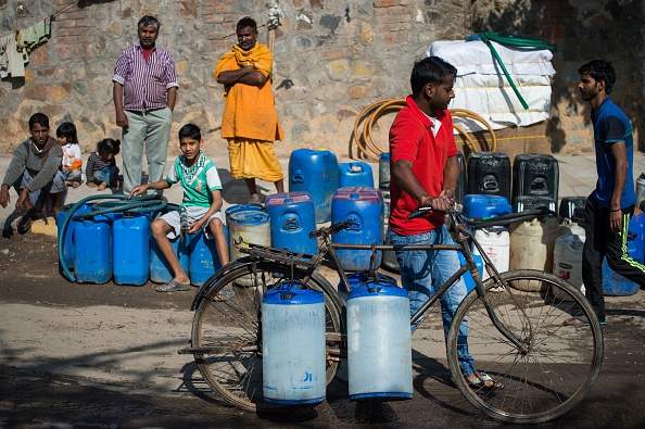 A resident of the eastern New Delhi neighborhood of Sanjay Camp pushes a bicycle loaded with water containers as he heads home after collecting the water from a water distribution point in the low income colony on February 23, 2016. 