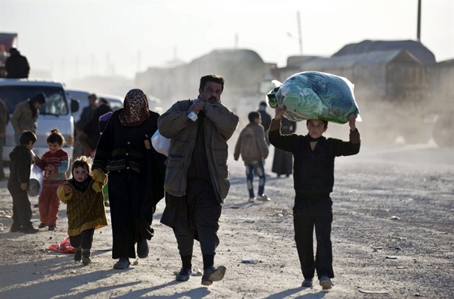 Syrians walk towards the Turkish border at the Bab al-Salam border gate, Syria, Friday, Feb. 5, 2016. Turkish officials say thousands of Syrians have massed on the Syrian side of the border seeking refuge in Turkey. Officials at the government’s crisis management agency said Friday it was not clear when Turkey would open the border to allow the group in and start processing them. The refugees who fled bombing in Aleppo, were waiting at the Bab al-Salam crossing, opposite the Turkish province of Kilis. (Depo Photos via AP) .