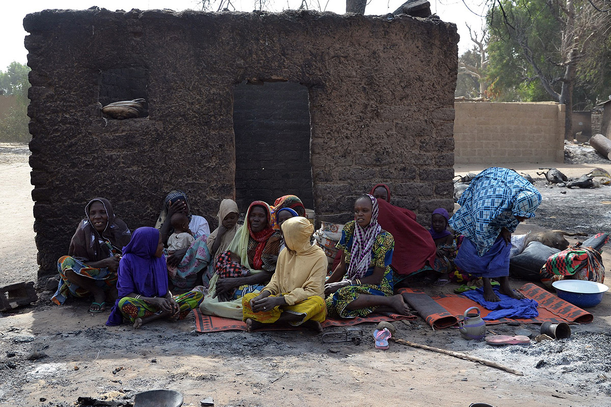 FILE: Women fleeing from Boko Haram Islamists sit with wares beside a burnt house at Mairi village outskirts of Maiduguri capital of northeast Borno State, on  February 6, 2016.  