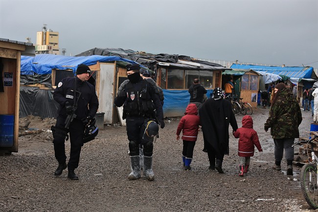 In this Feb. 5, 2016 photo, French riot police officers patrol in the migrant camp in Calais, north of France.