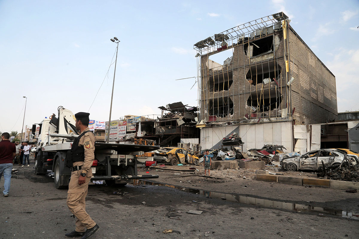 Security forces inspect the site of a car bomb explosion in the largely Shiite eastern neighborhood of Talibiyah in Baghdad, Iraq, Thursday, Oct. 16, 2014. A suicide bomber rammed his explosives-laden car into a police checkpoint Thursday in the Iraqi capital, killing more than 10 and wounding tens of people, Iraqi officials said. 