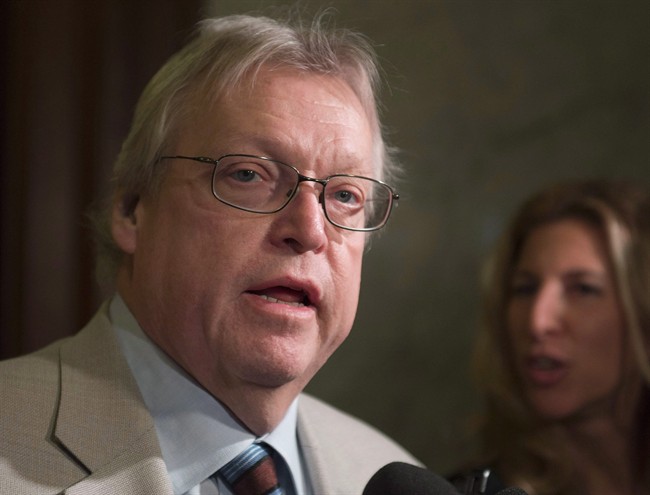 Quebec Health Minister Gaetan Barrette responds to reporters at the end of a caucus meeting.
