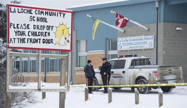 Members of the RCMP stand outside the La Loche Community School in La Loche, Sask. Monday, Jan. 25, 2016. THE CANADIAN PRESS/Jonathan Hayward.