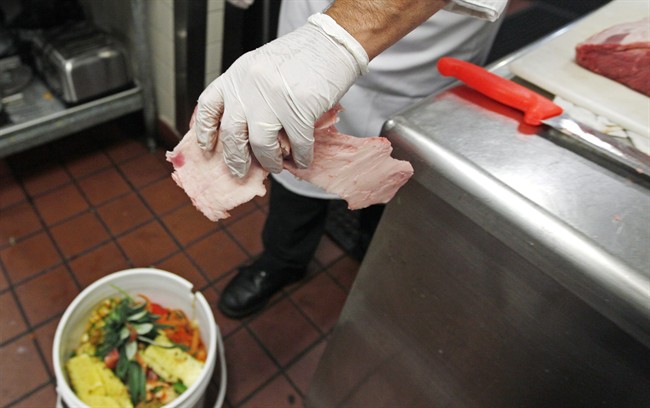 A chef drops beef scraps into a bucket of food waste in Middleton, Mass.