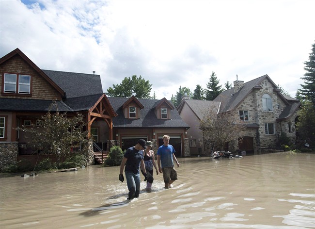 Residents walk through flood waters in Calgary on June 24, 2013.