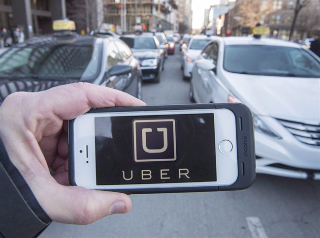 The Uber logo is seen in front of protesting taxi drivers at the Montreal courthouse, on February 2, 2016. Niagara police have charged 20 drivers with offences under the Highway Traffic Act.