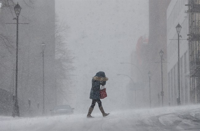 A woman shields her face from wind-swept snow during a winter storm in Halifax on Monday, Feb. 8, 2016.