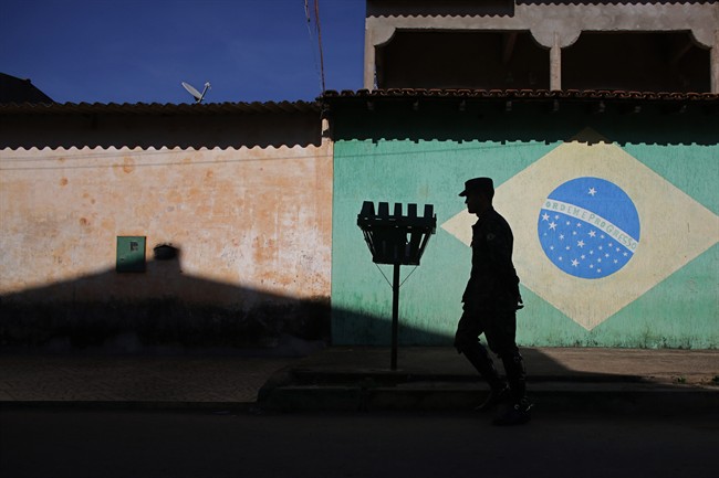 An army soldier walks in in front of a mural of the Brazilian flag during an operation to eradicate Aedes aegypti mosquito breeding sites, in the Brazlandia neighborhood of Brasilia, Brazil, Wednesday, Feb. 17, 2016. 