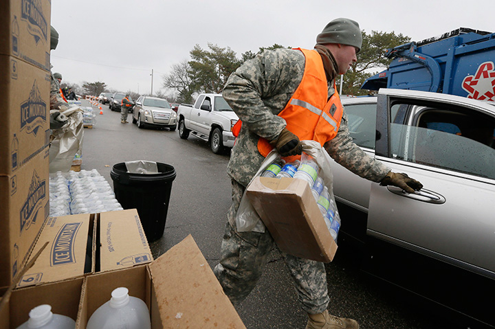 Members of the Michigan National Guard load bottled water for residents at a fire station, Thursday, Jan. 28, 2016 in Flint, Mich. 