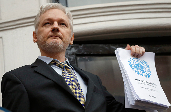 WikiLeaks founder Julian Assange holds a U.N. report as he speaks on the balcony of the Ecuadorean Embassy in London, Friday, Feb. 5, 2016.