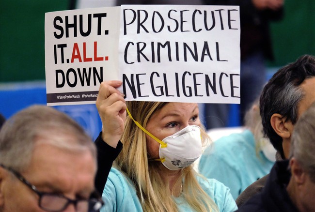 In this Jan. 16, 2016 file photo, Tera Lecuona, resident of the heavily-impacted Porter Ranch area of Los Angeles, holds a protest sign during a hearing in Granada Hills over a gas leak at Southern California Gas Company's Aliso Canyon Storage Facility.