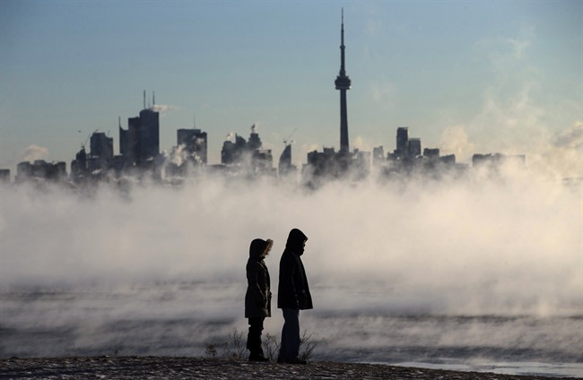 Steam rises as people look out on Lake Ontario in front of the skyline during extreme cold weather in Toronto on Saturday, February 13, 2016. THE CANADIAN PRESS/Mark Blinch.