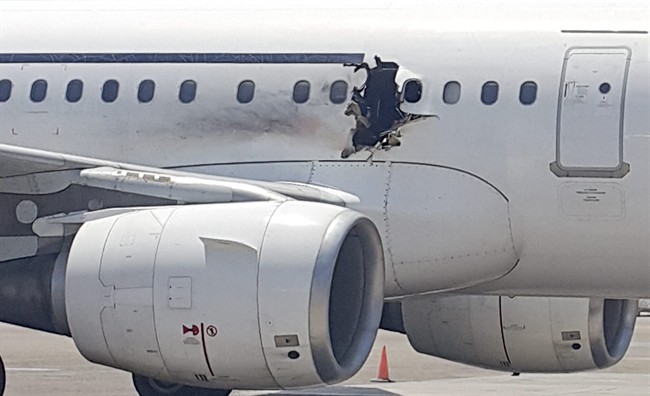 In this Tuesday, Feb. 2, 2016 photo, a hole is photographed in a plane operated by Daallo Airlines as it sits on the runway of the airport in Mogadishu, Somalia. A gaping hole in the commercial airliner forced it to make an emergency landing at Mogadishu's international airport late Tuesday, officials and witnesses said. (AP Photo).