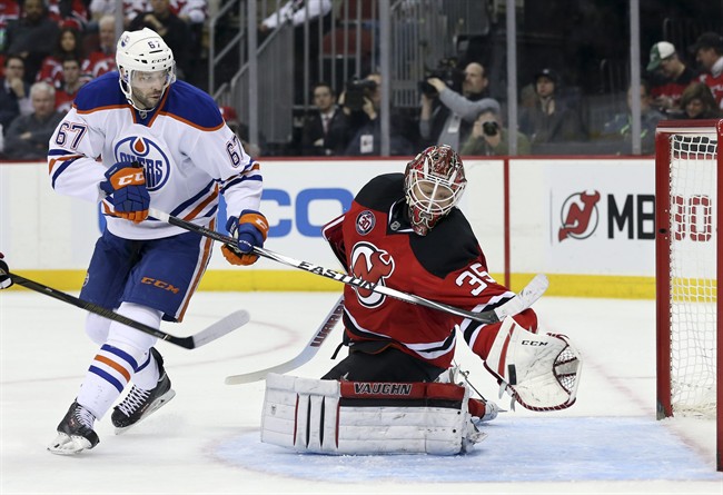 New Jersey Devils goalie Cory Schneider (35) makes a glove save on a shot by Edmonton Oilers left wing Benoit Pouliot (67) during the first period of an NHL hockey game Tuesday, Feb. 9, 2016, in Newark, N.J. 