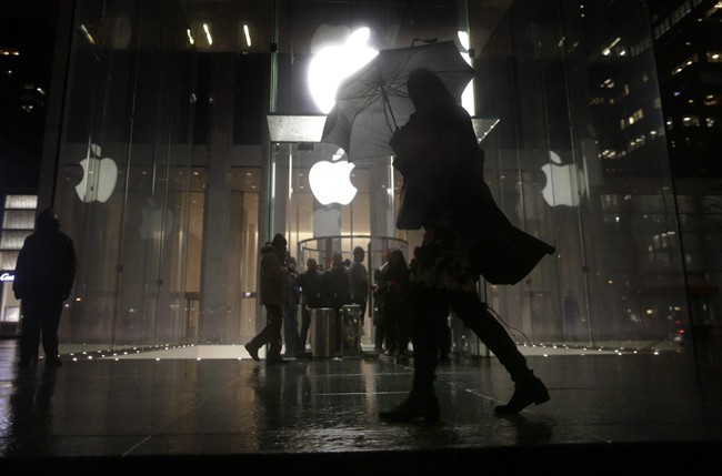 A pedestrian walks by the Apple Store on Fifth Avenue while avoiding a small demonstration held along the sidewalk, Tuesday, Feb. 23, 2016, in New York. Protesters assembled in more than 30 cities around the world to lash out at the FBI for obtaining a court order that requires Apple to make it easier to unlock an encrypted iPhone used by a gunman in December's mass murders in California.