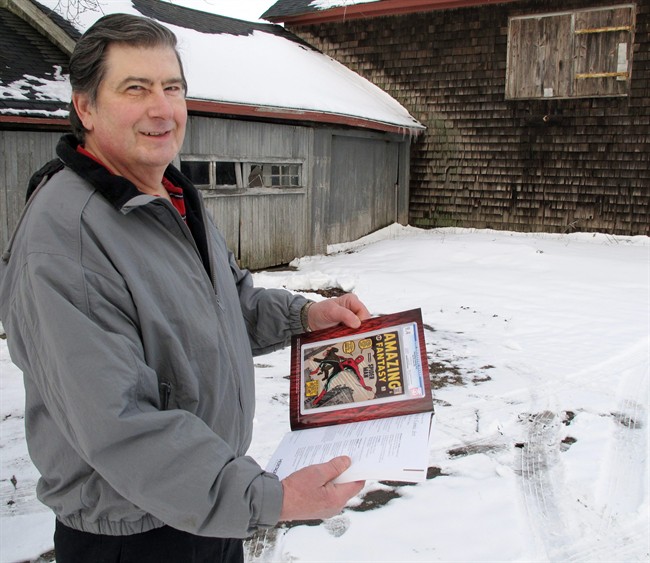 In this photo taken Tuesday, Feb. 9, 2016, in Calverton, N.Y., Walter Yacoboski holds an auction guide featuring one of his comic books, "Amazing Fantasy" No. 15, which features the Spider-Man character.