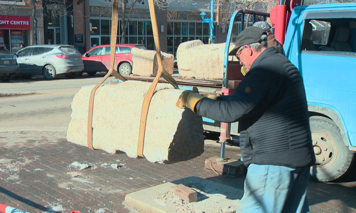 Workers cleaning up a damaged sculpture in downtown Saskatoon Tuesday afternoon.