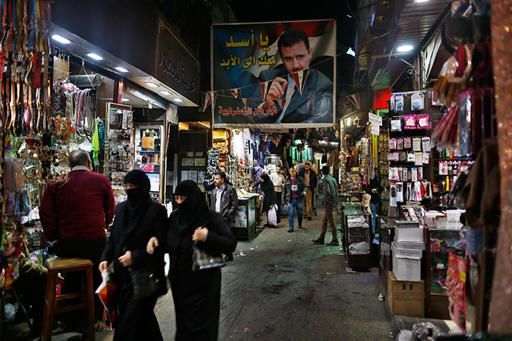 A poster of the Syrian President Bashar Assad with Arabic reads, "Assad we are with you for ever" hangs up at the popular Hamidiyeh old market in Damascus, Syria, Sunday, Feb. 21, 2016.  