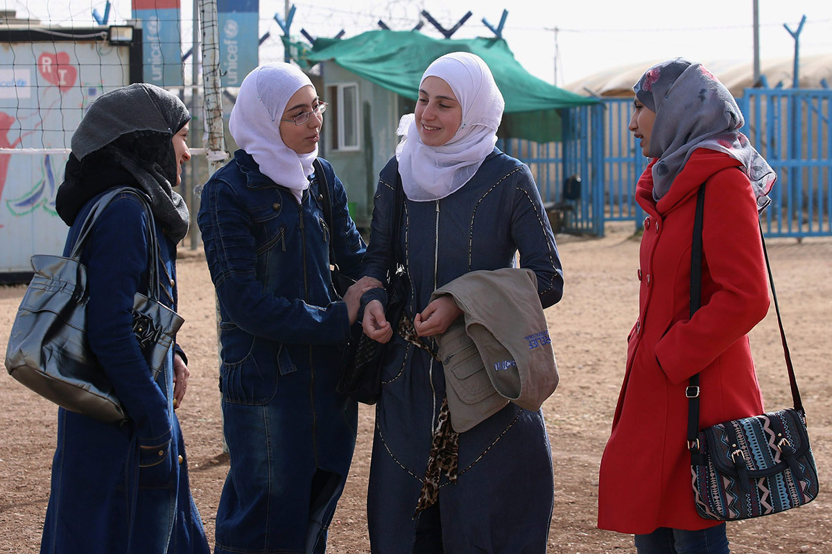In this Thursday, Jan. 21, 2016 photo, four young Syrian women stand outside a remedial education center in the Zaatari refugee camp near Mafraq, Jordan. The remedial classes are intended for students who need help keeping up in school, including those who missed classes due to the civil war in Syria. 
