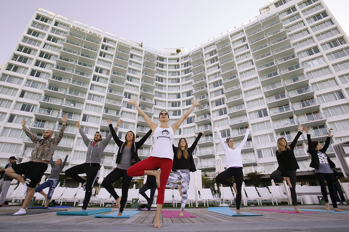 Paula Walker, center foreground, an instructor with Green Monkey Yoga, leads a yoga class at the Mondrian South Beach Hotel in Miami Beach, Fla. The hotel world is moving beyond basement gyms and ho-hum spa menus to accommodate guests’ growing requests to stay healthy while on the road.