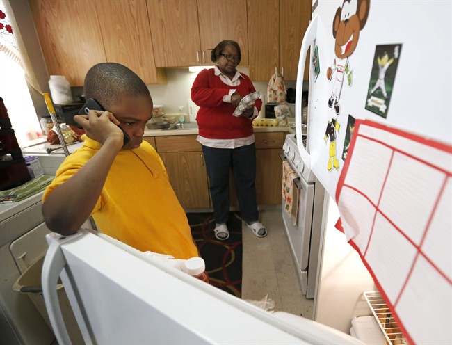 In this Jan. 29, 2016, photo, Debra Aldridge, right, continues to make dinner as her grandson Mario Hendricks talks to a cousin about being able to go to a sleep-over at the cousin's home, at her home on Chicago's South Side. Nationwide, there are 2.7 million grandparents raising grandchildren. About a fifth have incomes that fall below the poverty line, according the Census figures.