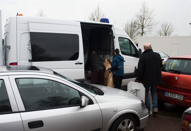 Members of the German police load seized items into vehicles parked in front of the reception facility for refugees located in a gymnasium in Attendorn, Germany, Thursday Feb. 4, 2016. 