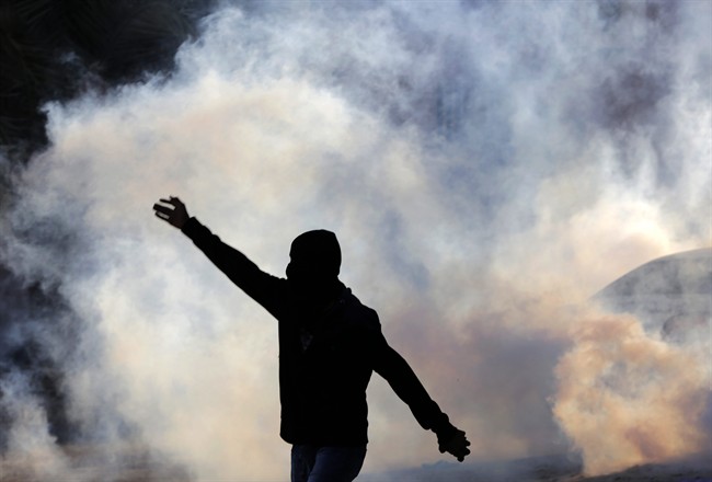 A Bahraini anti-government protester stands amid clouds of tear gas fired by riot police during clashes in Sitra, Bahrain, on Sunday, Feb. 14, 2016. 