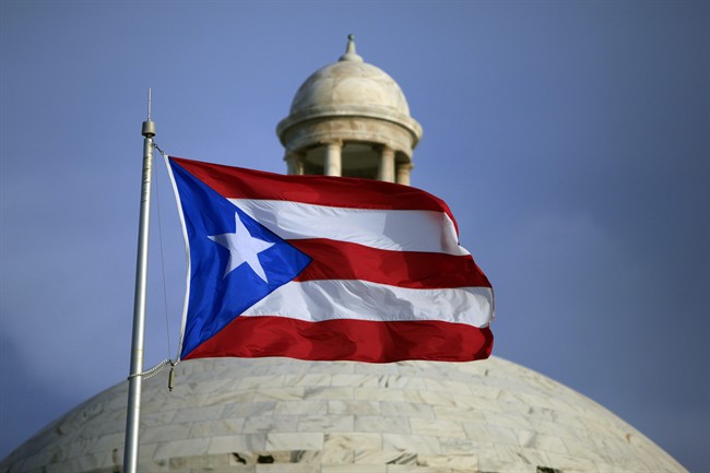 In this Wednesday, July 29, file 2015 photo, the Puerto Rican flag flies in front of Puerto Rico’s Capitol as in San Juan, Puerto Rico.