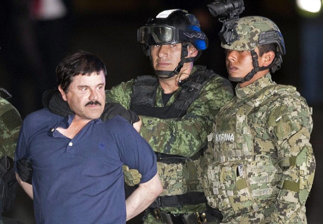 In this Jan. 8, 2016 file photo, Joaquin "El Chapo" Guzman is forced to face the press as he is escorted to a helicopter in handcuffs by Mexican soldiers in Mexico City.