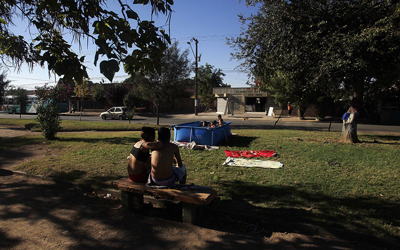 A couple sits near a park in a residential area of Santiago, Chile. 