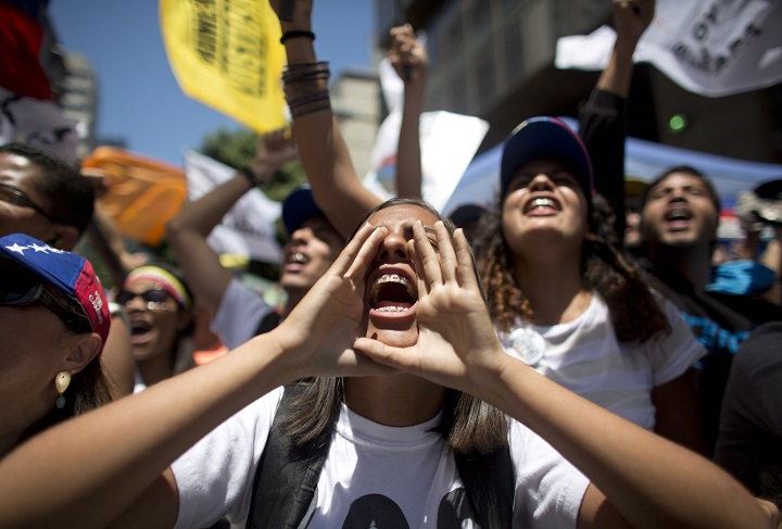 A woman cups her hands around her mouth as she shouts with others during an opposition protest in Caracas, Venezuela, Saturday, March 12, 2016.