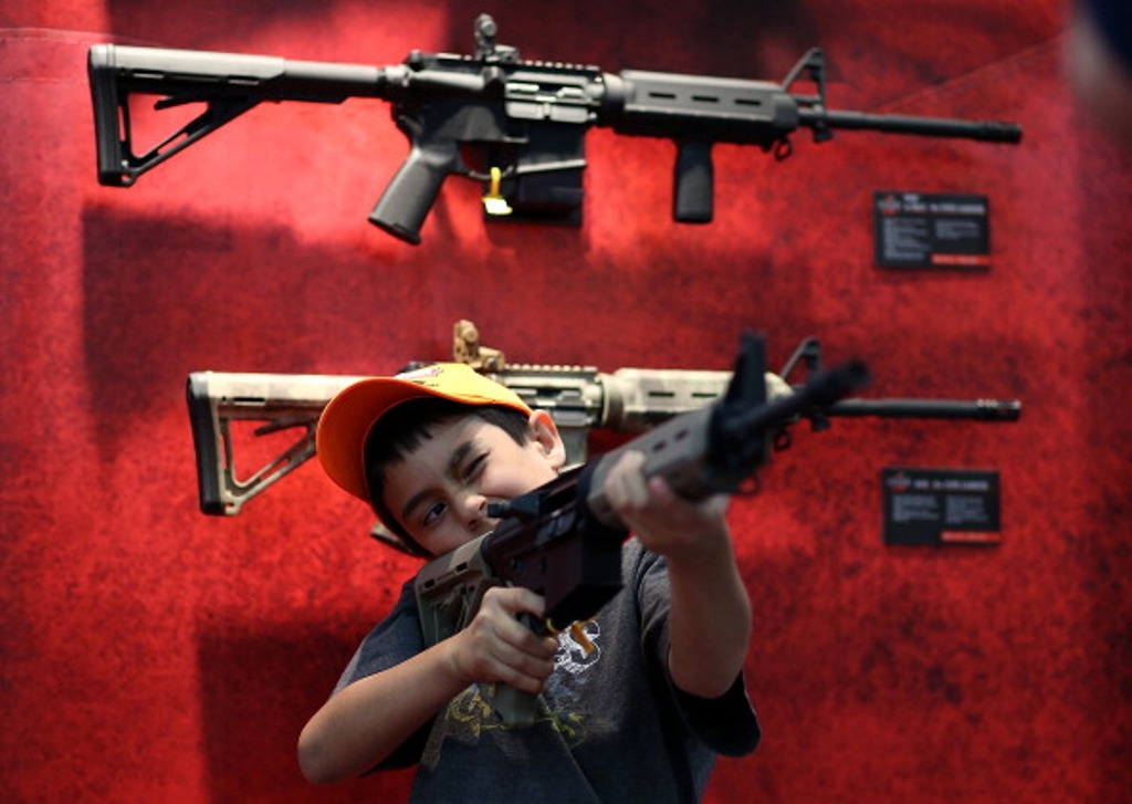 An young attendee inspects an assault rifle during the 2013 NRA Annual Meeting and Exhibits at the George R. Brown Convention Center on May 4, 2013 in Houston, Texas.