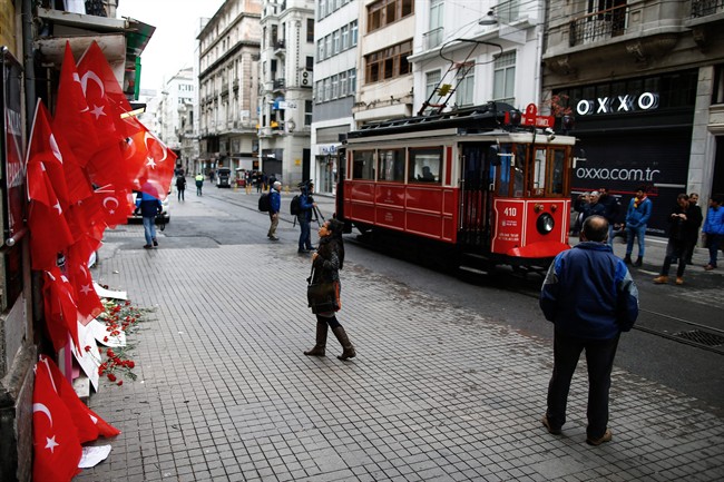 A tourist looks at carnations and messages left by people at the Saturday explosion site in Istanbul, Sunday, March 20, 2016. A suicide attack on Istanbul's main pedestrian shopping street Saturday killed a number of people, including two dual nationality Israeli-Americans and one Iranian citizen, and wounded several dozen others, in the sixth suicide bombing in Turkey in the past year. 