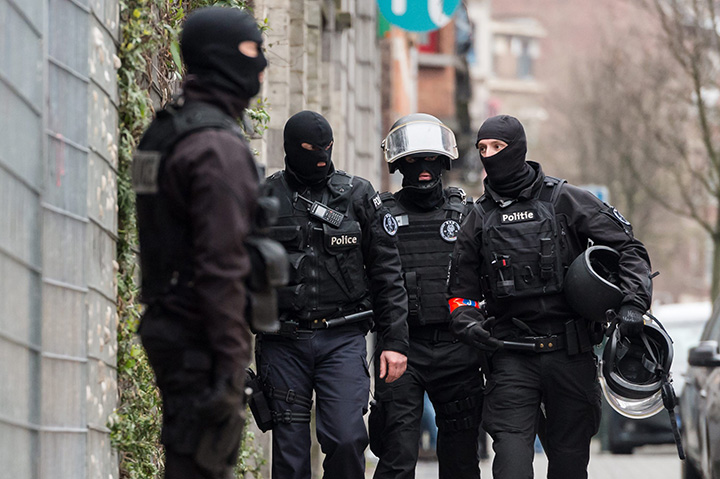 Police officers stand guard during a raid in the Molenbeek neighbourhood of Brussels, Belgium, Friday March 18, 2016.
