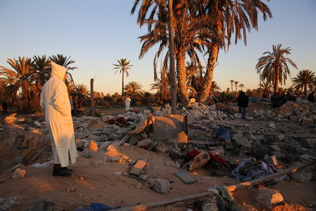 In this Feb. 19, 2016 file photo, people gather after U.S. airstrikes on a house and training camp belonging to the Islamic State group, west of Sabratha, Libya. Canada's top general says it is not yet decided if Canada will join other western troops in the country.
