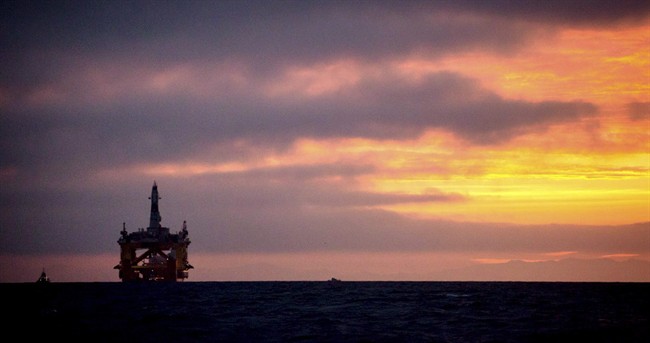 In this April 17, 2015 file photo, an oil drilling rig arrives aboard a transport ship at sunrise, following a journey across the Pacific in Port Angeles, Wash. 