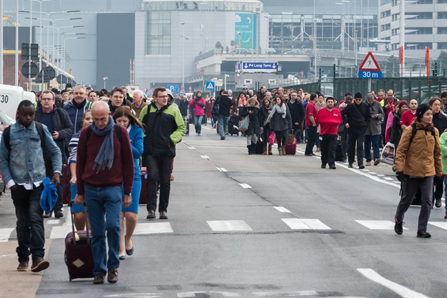 People walk away from Brussels airport after explosions rocked the facility in Brussels, Belgium Tuesday March 22, 2016.