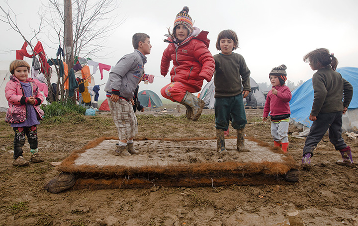 Migrant children play on a muddy mattress at the northern Greek border point of Idomeni, Greece, Friday, March 18, 2016. 