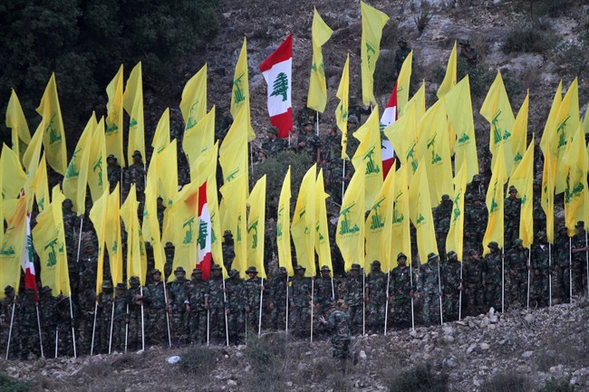In this August 14, 2015, file photo, Hezbollah fighters hold their group and Lebanese flags, as they perform during a rally marking the ninth anniversary of the 2006 Israel-Hezbollah war, at the southern Lebanese village of Wadi al-Hujair, Lebanon.