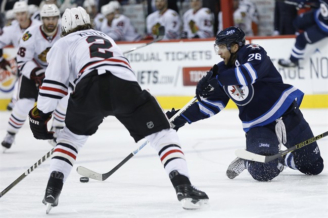 Winnipeg Jets' Blake Wheeler (26) plays the puck after getting tripped and Chicago Blackhawks' Duncan Keith (2) defends during second period NHL action in Winnipeg on Friday, March 18, 2016. 