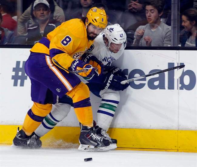 Los Angeles Kings defenceman Drew Doughty (8) stops Vancouver Canucks left wing Sven Baertschi, right, of Switzerland, with a check against the boards during the first period of an NHL hockey game in Los Angeles, Monday, March 7, 2016.