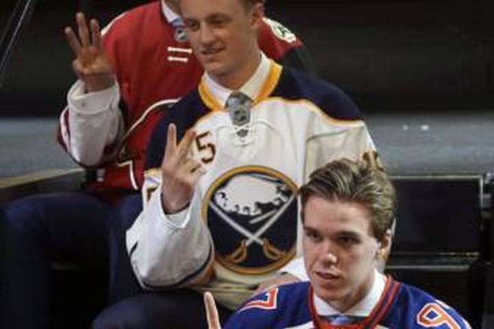 Connor McDavid, foreground, first overall pick; Jack Eichel, center, second overall pick; and Dylan Strome, third overall pick; pose for cameras during the first round of the NHL hockey draft, Friday, June 26, 2015, in Sunrise, Fla. Linked together even before they were selected with the first two picks of the NHL Draft last June, McDavid and Eichel continue to travel a similar path.