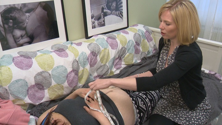 Cassie Evans, a Calgary registered midwife measures her 24-week pregnant patient in this file photo.