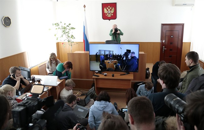 Journalists, who were not let in a courtroom, make photos of a TV screen showing a glass cage where Nadezhda Savchenko sits, in a town of Donetsk, Rostov-on-Don region, Monday, March 21, 2016. A judge in the border Russian town is expected to deliver a verdict in the case of Ukrainian pilot Savchenko, charged with complicity to murder in the deaths of two Russian journalists in warring eastern Ukraine. The judge in Savchenko's trial is expected to begin reading the verdict on Monday but the sentencing is likely to be announced on Tuesday. (AP Photo/Ivan Sekretarev).