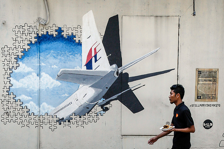 In this Feb. 23, 2016 file photo, a waiter walks past a mural of Malaysia Airlines Flight 370, in Shah Alam outside Kuala Lumpur, Malaysia. 