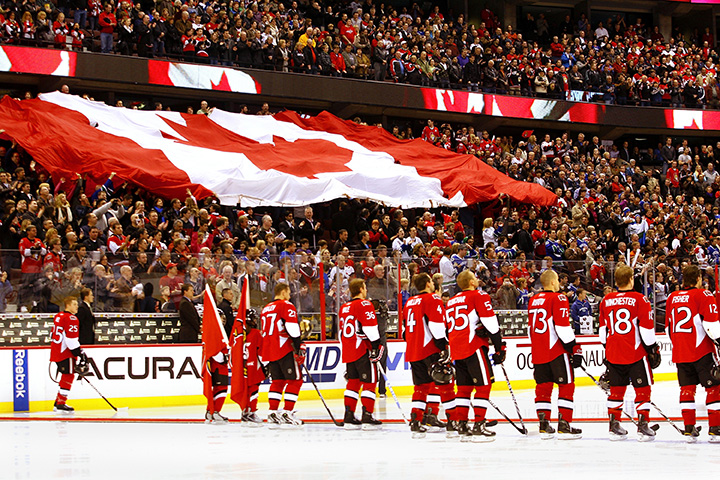 The Ottawa Senators stand at the blue line as the Canadian flag passes through the crowd prior to a game against the Vancouver Canucks on at Scotiabank Place on November 11, 2010 in Ottawa.  
